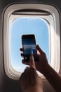 A passanger is taking photo with her smartphone in airplane and watching the view from window. Royalty Free Stock Photo