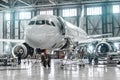 Passenger aircraft on maintenance of engine and fuselage repair in airport hangar.