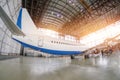 Passenger aircraft on maintenance of engine and fuselage repair in airport hangar. Rear view, under the tail