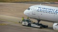 The passenger aircraft is pushed backwards over the tarmac with the aircraft tractor, close up view