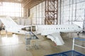 Passenger aircraft, side view - on maintenance of engine on tail and fuselage repair in airport hangar. Royalty Free Stock Photo