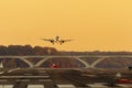 A passenger airline is slowly descending to land on a runway at sunset.