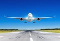 Passenger airplane with bright landing lights landing at in good clear weather with a blue sky on a runway. Royalty Free Stock Photo