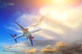 Passenger airplane in the cloud of unusual shape and sunset sunlight among the clouds. travel by air transport Royalty Free Stock Photo