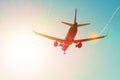 Passenger airplane flies near the sun glare with a color rainbow gradient on landing, with the wings of a steam jet vortex. Royalty Free Stock Photo