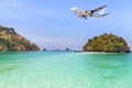 Passenger airplane flying above small island in tropical andaman sea. Royalty Free Stock Photo