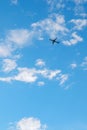 The passenger airplane is flying far away in the blue sky and white clouds. Plane in the air. International passenger air