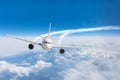 Passenger airplane flying at flight level high in the sky above the clouds and blue sky Royalty Free Stock Photo