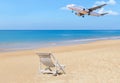 Passenger airplane flying landing above tropical beach with white wooden beach chair Royalty Free Stock Photo
