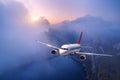 Passenger airplane is flying over clouds at sunset Royalty Free Stock Photo