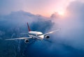 Passenger airplane is flying over clouds at sunset Royalty Free Stock Photo