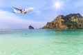 Passenger airplane landing above small island in blue sea Royalty Free Stock Photo