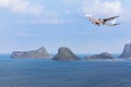 Passenger airplane landing above small island in blue sea Royalty Free Stock Photo