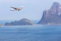 Passenger airplane landing above small island in blue sea and tropical beach Royalty Free Stock Photo