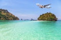 Passenger airplane landing above small island in blue sea Royalty Free Stock Photo