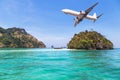 Passenger airplane landing above small island in blue sea and tropical beach Royalty Free Stock Photo