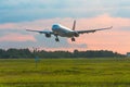 Passenger airplane landing on runway at airport, early evening Royalty Free Stock Photo