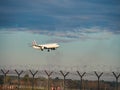 Passenger airplane is landing in runway. Protected area of international airport. Plane released landing gear flying