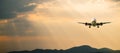 Passenger airplane. Landscape with Front of white airplane is flying in the orange sky with clouds over mountains Royalty Free Stock Photo