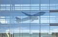 Passenger airplane leaving non existent modern airport seen as reflection in glass facade Royalty Free Stock Photo