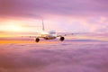 Passenger airplane in the morning sun flies high above the pink-tinted clouds with glare on the fuselage Royalty Free Stock Photo