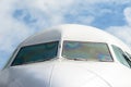 Passenger airplane nose cockpit in blue clouds sky. Royalty Free Stock Photo