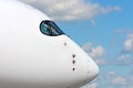 Passenger airplane nose cockpit in blue clouds sky. Royalty Free Stock Photo