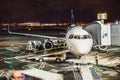 Passenger airplane on runway near the terminal in an airport at night time. Airport land crew doing flight service for passenger a Royalty Free Stock Photo