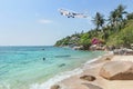 Passenger airplane take off above tropical beach with blue sea on blue sky. Royalty Free Stock Photo