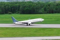 Passenger airplane takes off from the runway against the green forest Royalty Free Stock Photo