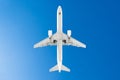 Passenger airplane. View exactly from below, white silhouette against the blue sky. Royalty Free Stock Photo