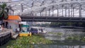 Passenger boat approaching floating dock on murky polluted Pasig River under the iron bridge