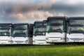 Passenger buses in a row in front of a meadow