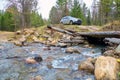 A passenger car stands in front of a destroyed old automobile bridge against the backdrop