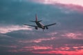 Passenger or cargo plane flies against the background of a red sky at sunset Royalty Free Stock Photo