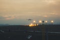 A passenger or cargo plane lands on the runway against the background of sunset, several people are watching the landing Royalty Free Stock Photo