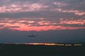 A passenger or cargo plane lands on the runway against the background of red sunset Royalty Free Stock Photo