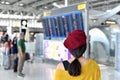 Passenger checking flight status at airport information display, Asian traveler looking at departure and arrival board. Royalty Free Stock Photo