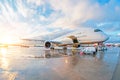 Passenger commercial aircraft parked with a wet apron at the airport during service maintenance evening rain at sunset with