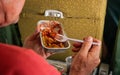 Passenger eating airplane food, pasta and sauce from aluminium container, wit plastic fork, detail from behind