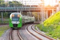 Passenger electric train rides on the turn of the railway line under the automobile bridge Royalty Free Stock Photo