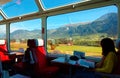 A passenger enjoying the idyllic scenery of Swiss countryside through the wide panoramic windows