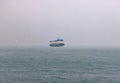 Passenger ferry navigates through fog in whiteout conditions on rainy day