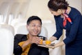 Passenger have orange juice served by an air hostess in airplane, Flight attendants serve on board Royalty Free Stock Photo