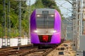 Passenger lilac violet electric train departs from the station platform and rides Royalty Free Stock Photo