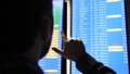 Passenger looking at timetable screen board and pointing with a finger searching for the right flight.