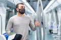 Passenger in mask holding on to handrails in subway car