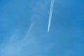 Passenger plane on a background of clear blue sky. A long stream of smoke escapes from the engines of a jet aircraft. Condensation