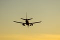 Passenger plane descending against yellow sky