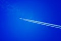 A passenger plane flies against a blue sky. White trace from the turbines of the aircraft. Royalty Free Stock Photo